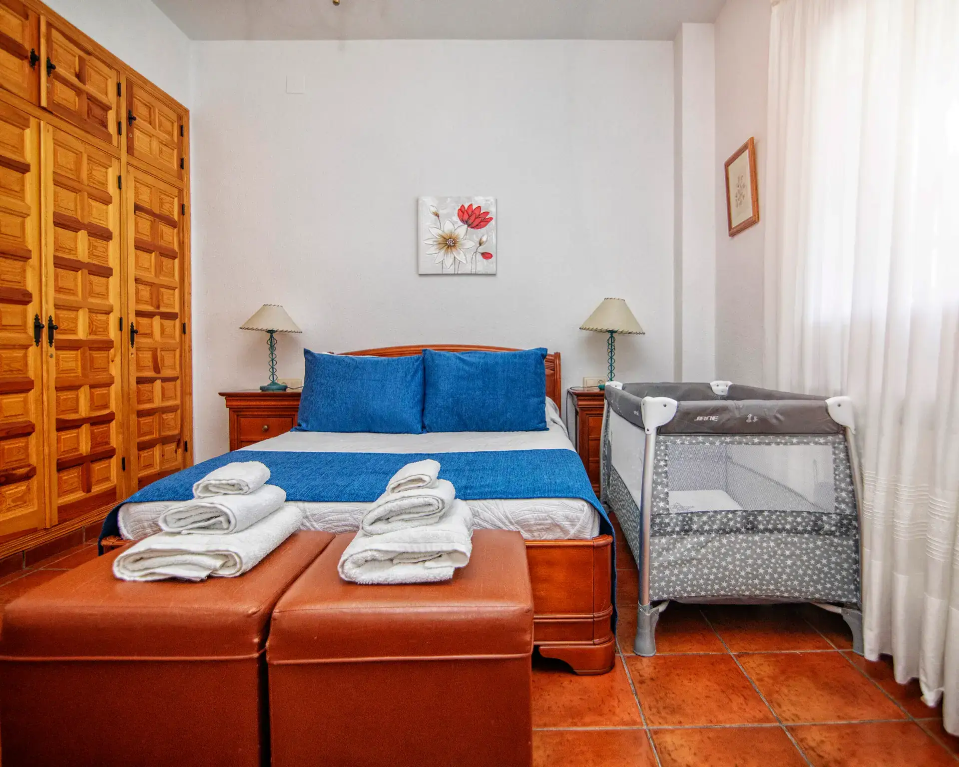 Dormitorio con dos camas y cuna, luz natural de la ventana