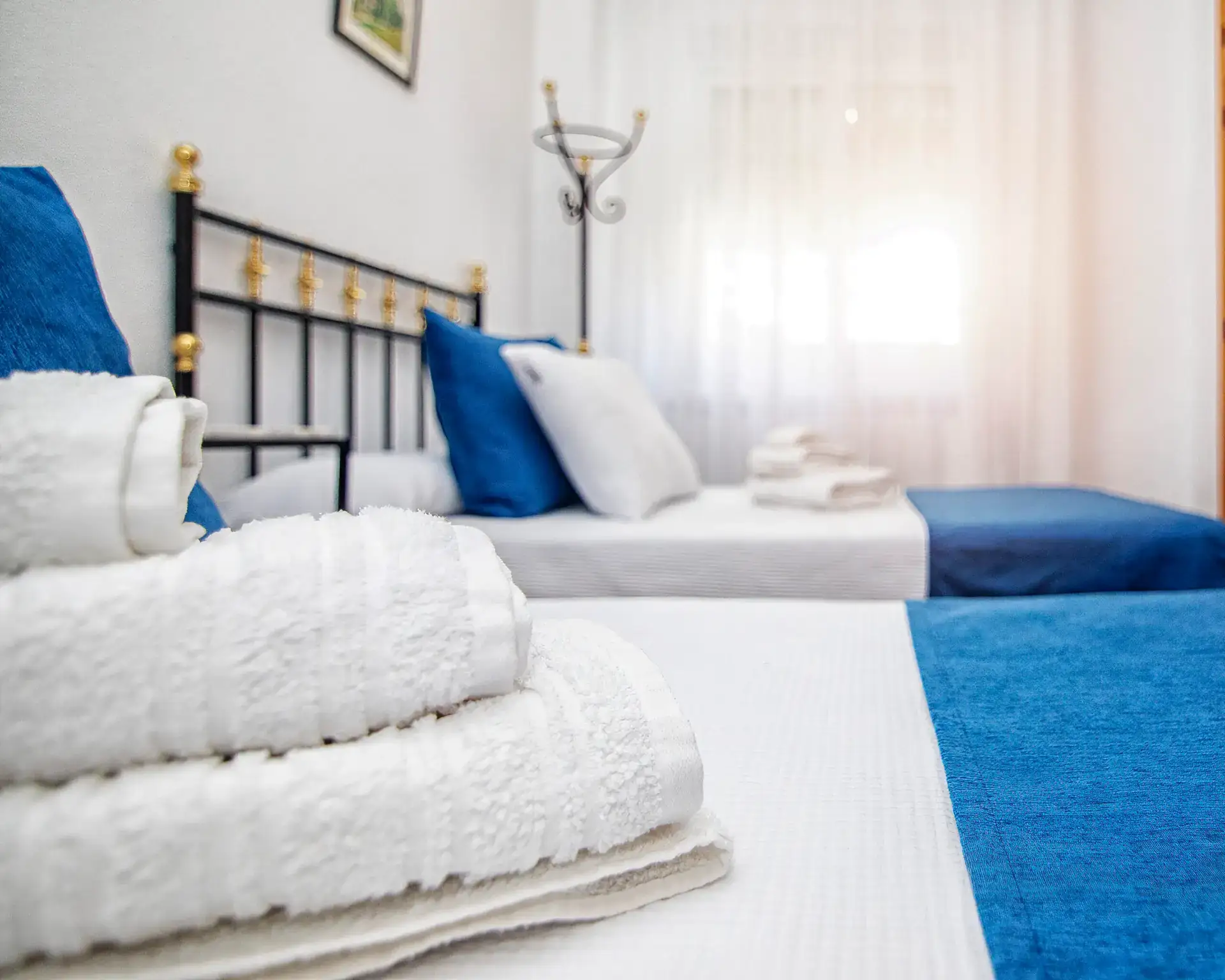 Detalle de la cama con toallas dobladas y luz de la ventana