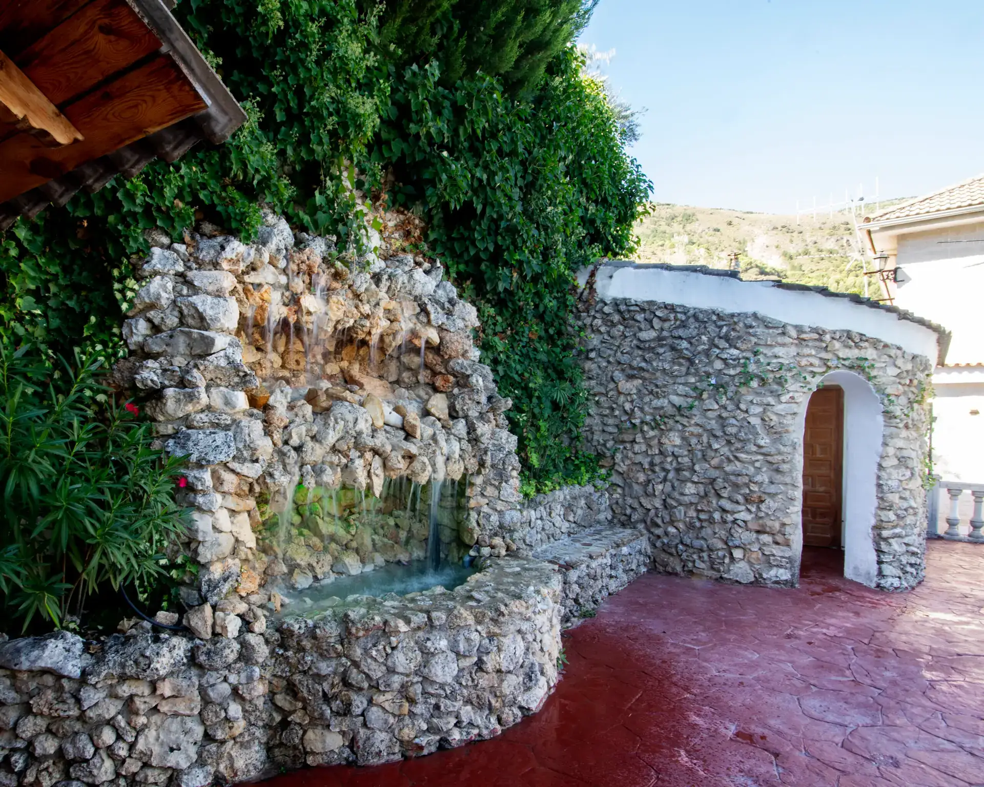 Gruta de piedra con fuente de agua en el jardín