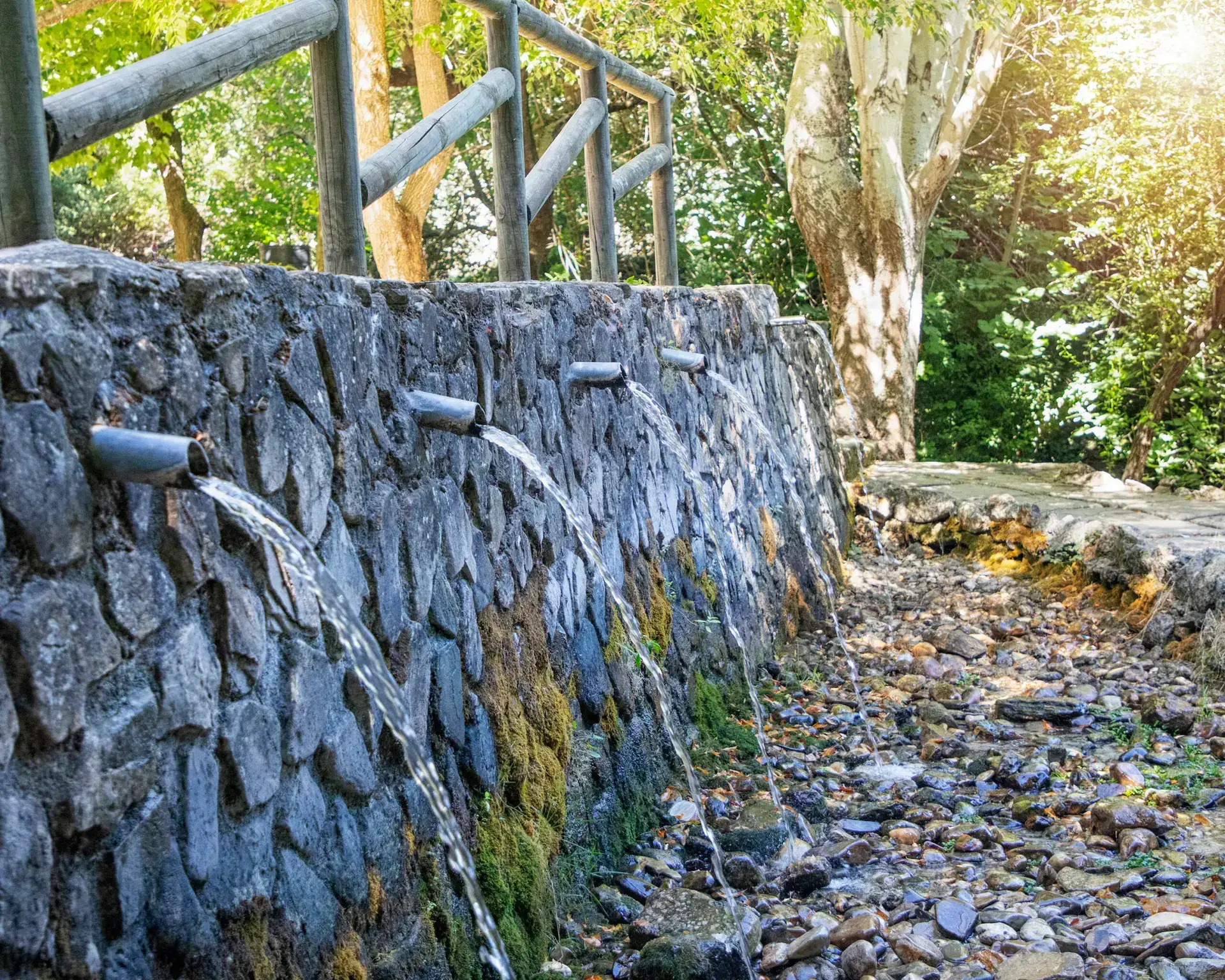 Caños de agua sobre el muro de piedra del jardín
