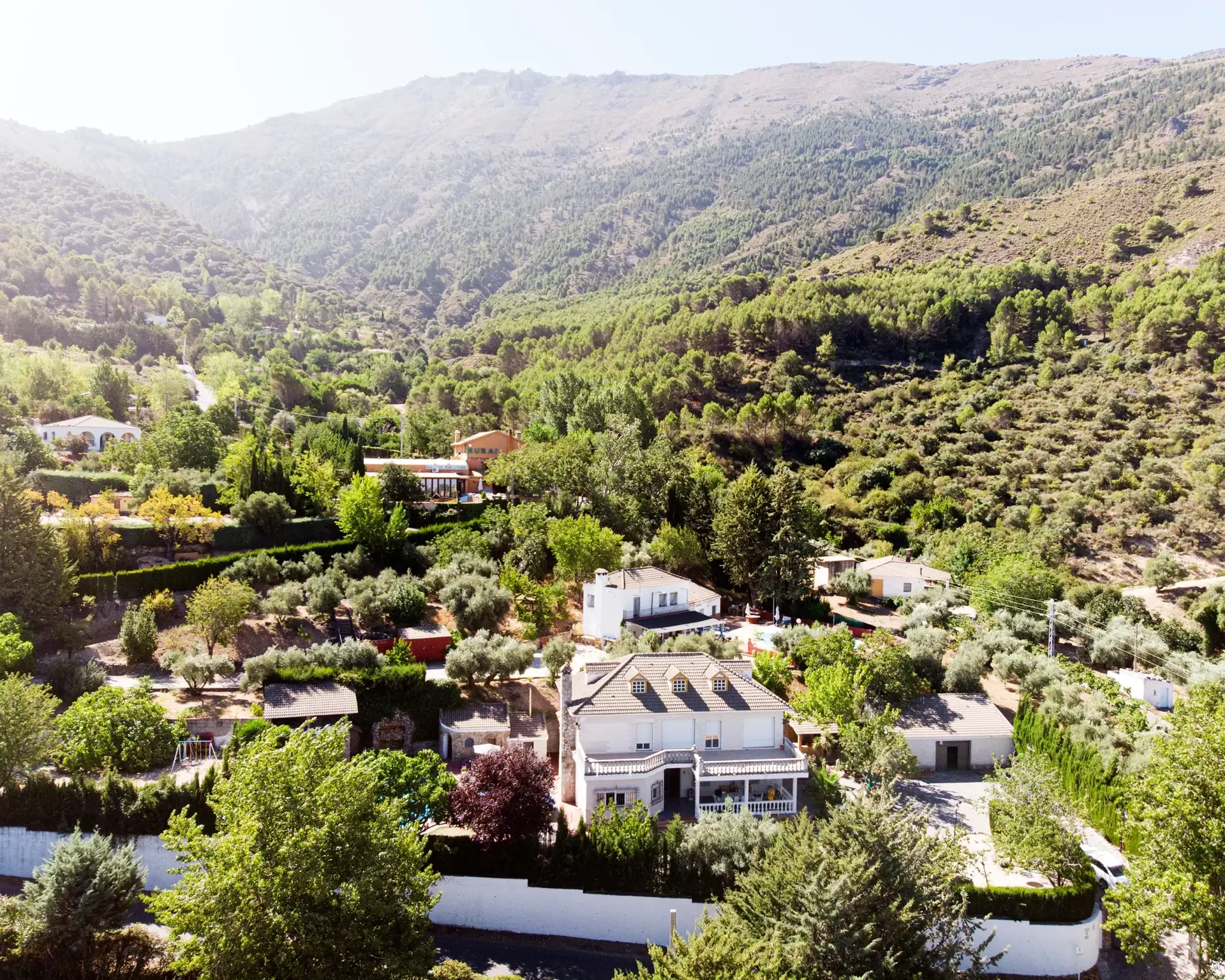 La casa vista desde el valle, rodeada de olivos y montaña